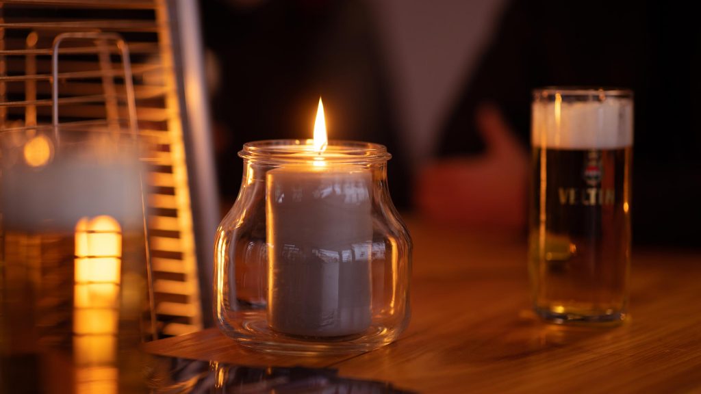 Kerze und Bierglas auf einem Holztisch am Abend